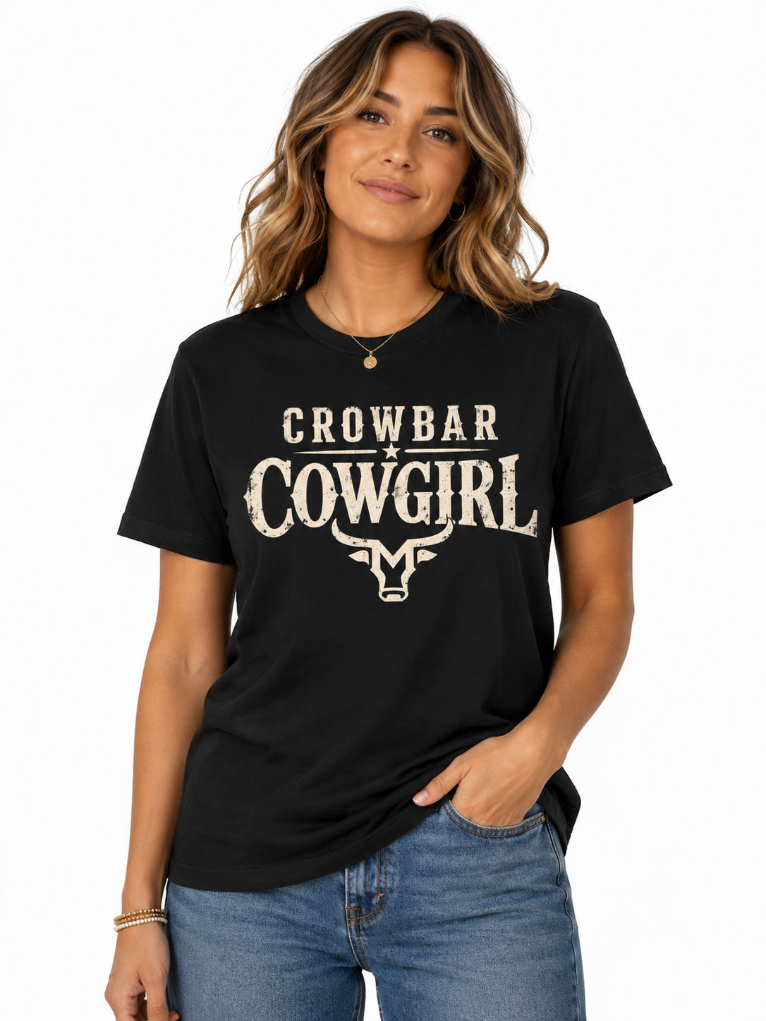 A woman wearing a black short-sleeve graphic T-shirt with distressed white text reading 'CROWBAR COWGIRL' and a bull skull motif, paired with blue jeans, against a plain white background.